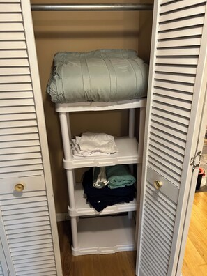 Un armario con tres repisas, una barra para colgar ropa y una puerta con picaporte de latón.