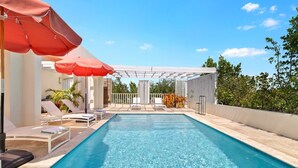 A swimming pool with lounge chairs and a pergola structure.