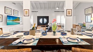 A dining area with a table set for four, a TV mounted on the wall, and framed artwork on the walls.