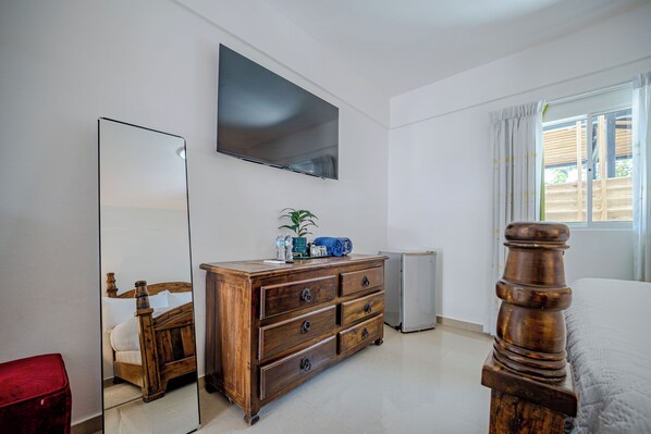 A bedroom with a bed, a dresser, a mirror, a television, and a window with curtains. - Hotel Boutique Villas Del Lago (El Factor)