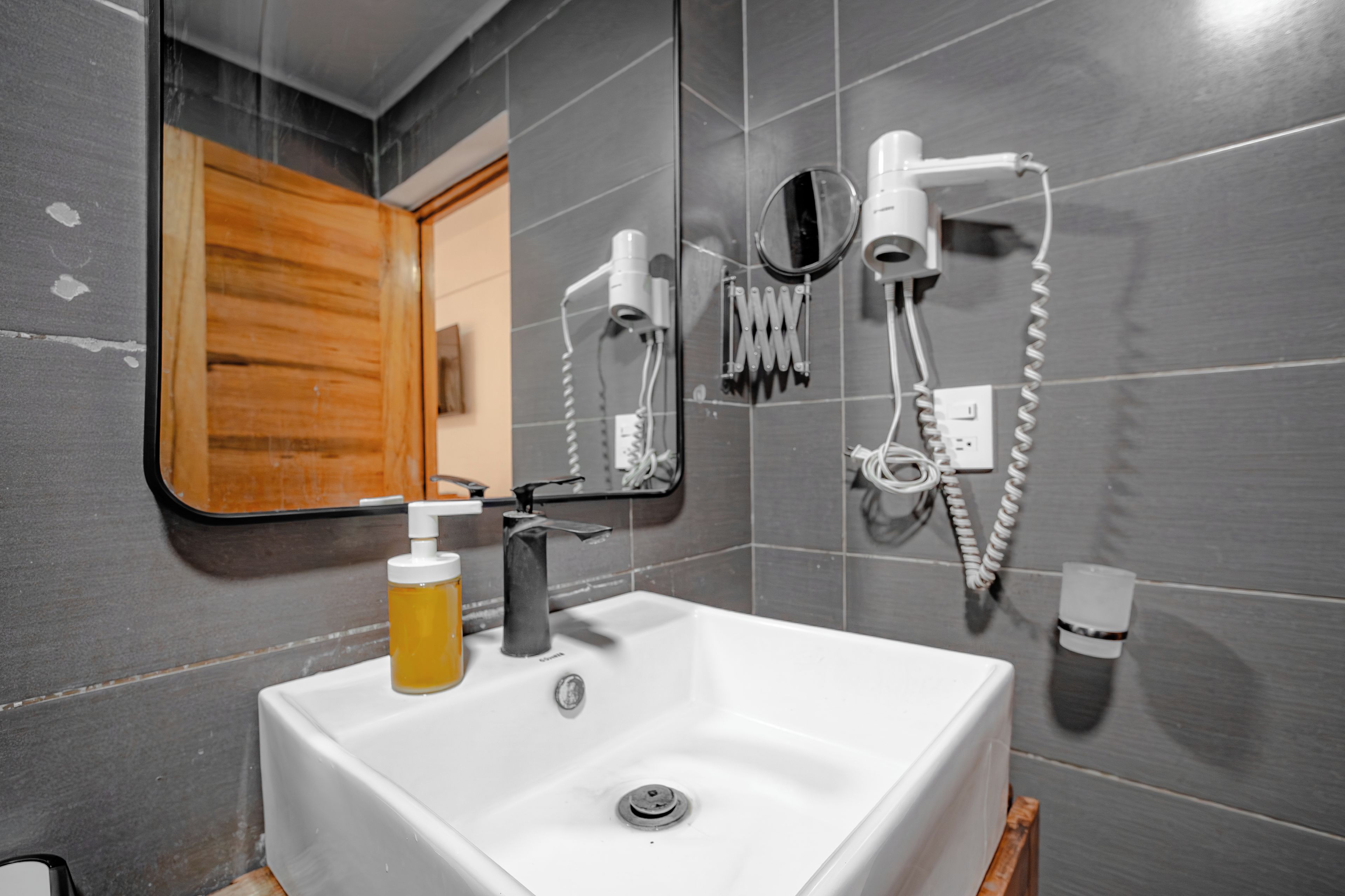 A bathroom with a white sink, a mirror, a hairdryer, and a towel rack.