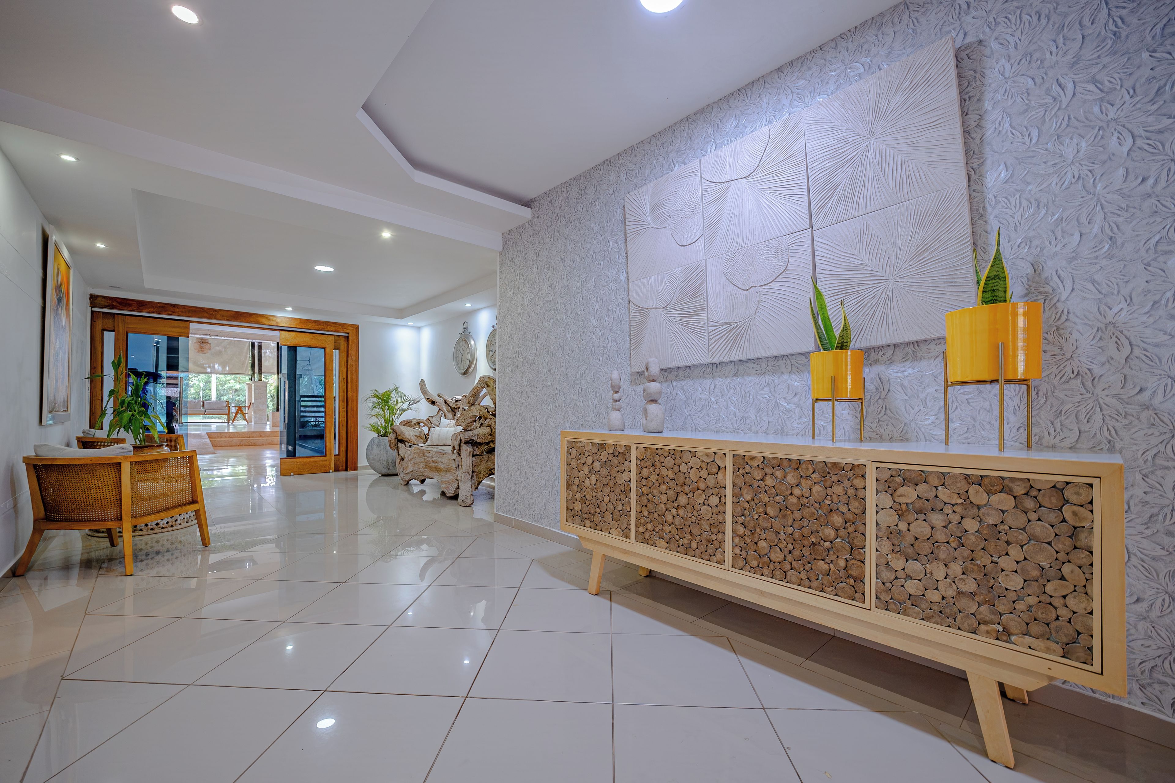 A modern lobby with a wooden console, decorative wall panels, and a tiled floor.