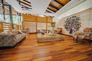 Un salón espacioso con techo alto, piso de madera y un gran mural en la pared.