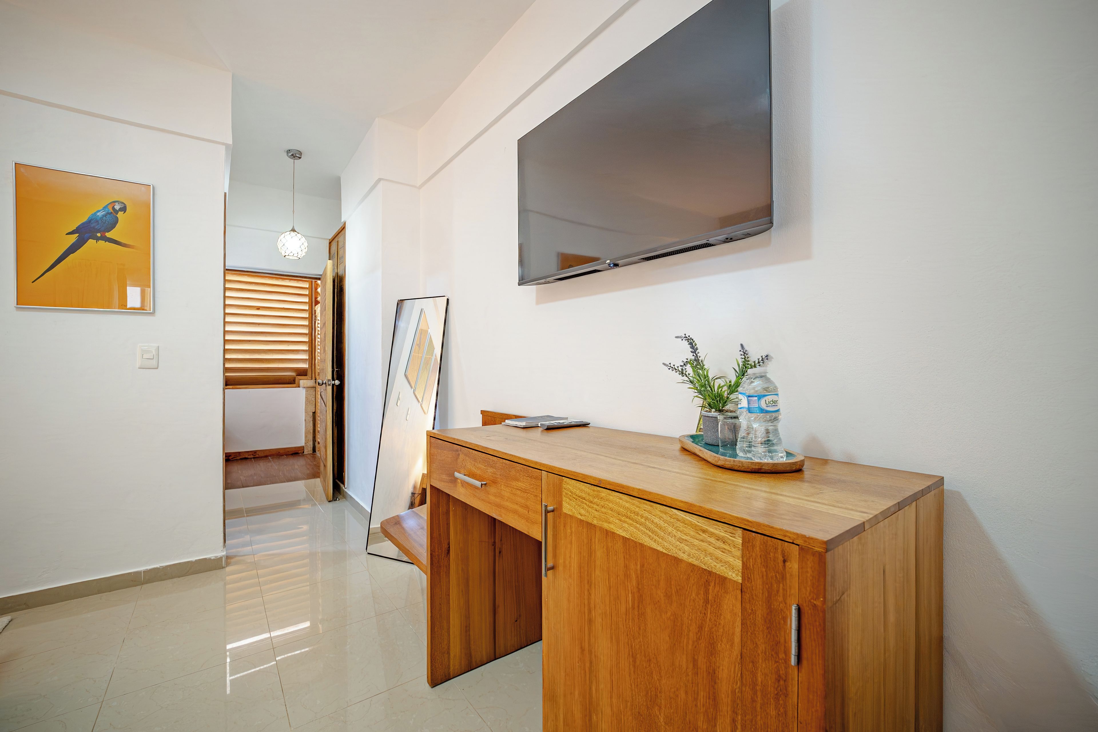 A modern room with a wooden desk, a flat-screen TV mounted on the wall, and a framed artwork on the wall.