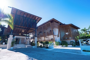 A modern building with a sloped roof, large windows, and a paved entrance area with steps. - Hotel Boutique Villas Del Lago (El Factor)