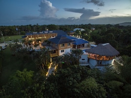 Um resort com vários edifícios, incluindo uma estrutura grande com telhado azul e um prédio menor com telhado de palha.