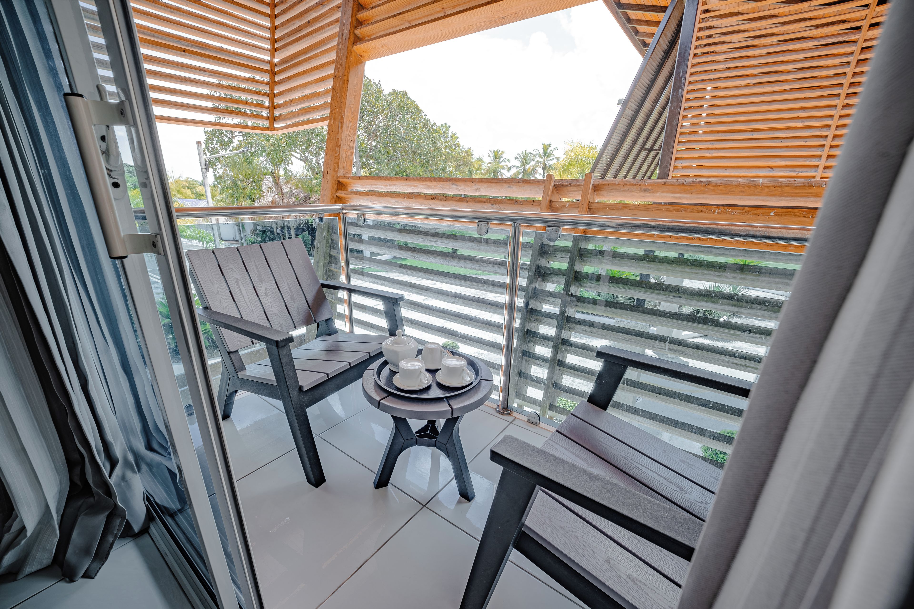 Ein Balkon mit Holztisch, gedeckter Kaffeetafel, einem Stuhl und Blick ins Grüne.