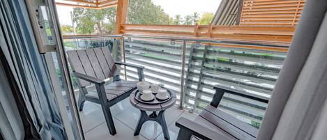 Ein Balkon mit Holztisch, gedeckter Kaffeetafel, einem Stuhl und Blick ins Grüne.