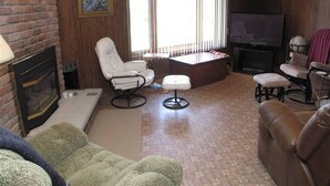Ein Wohnzimmer mit Kamin, Fernseher und einer gemütlichen Sitzecke.
