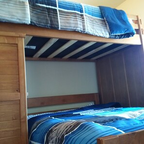 A bunk bed with a wooden frame and a blue and white striped blanket.