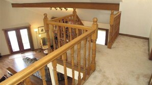 Eine Holztreppe mit Teppichboden, einem Bücherregal und einer Tür mit Glasfeldern.