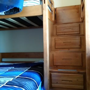 A bunk bed with a wooden ladder and drawers.