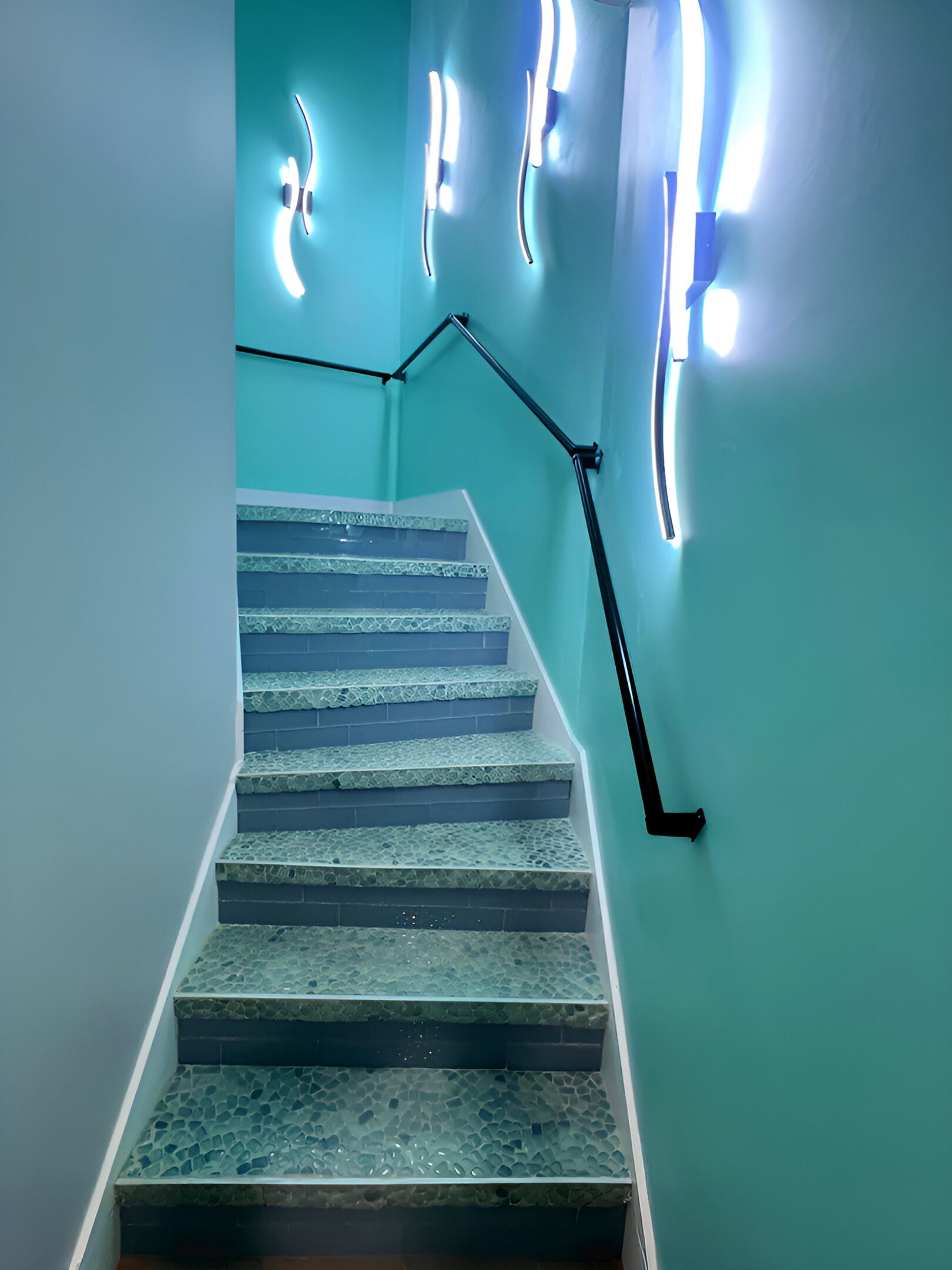 A staircase with a handrail and a wall with light fixtures.