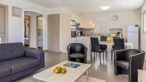 Ein modernes Wohnzimmer mit einer Couch, einem Esstisch mit Stühlen und einer Küchenzeile mit Geräten.