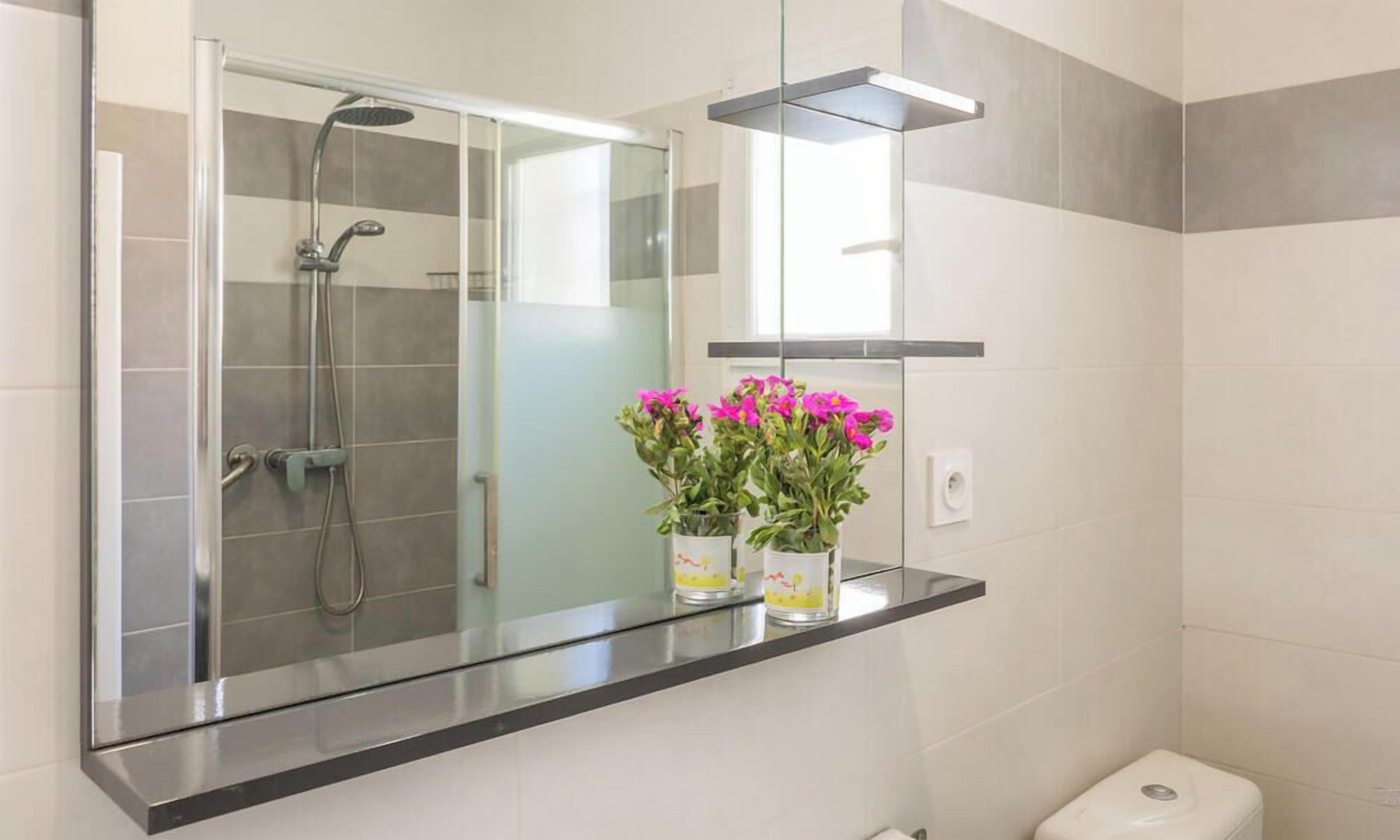 Un bagno moderno con cabina doccia in vetro, un water e uno scaffale con piante in vaso.