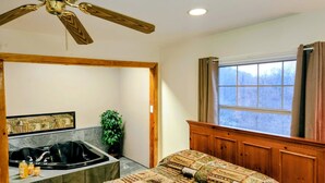 A bathroom with a bathtub, a shower, a window with curtains, and a ceiling fan.