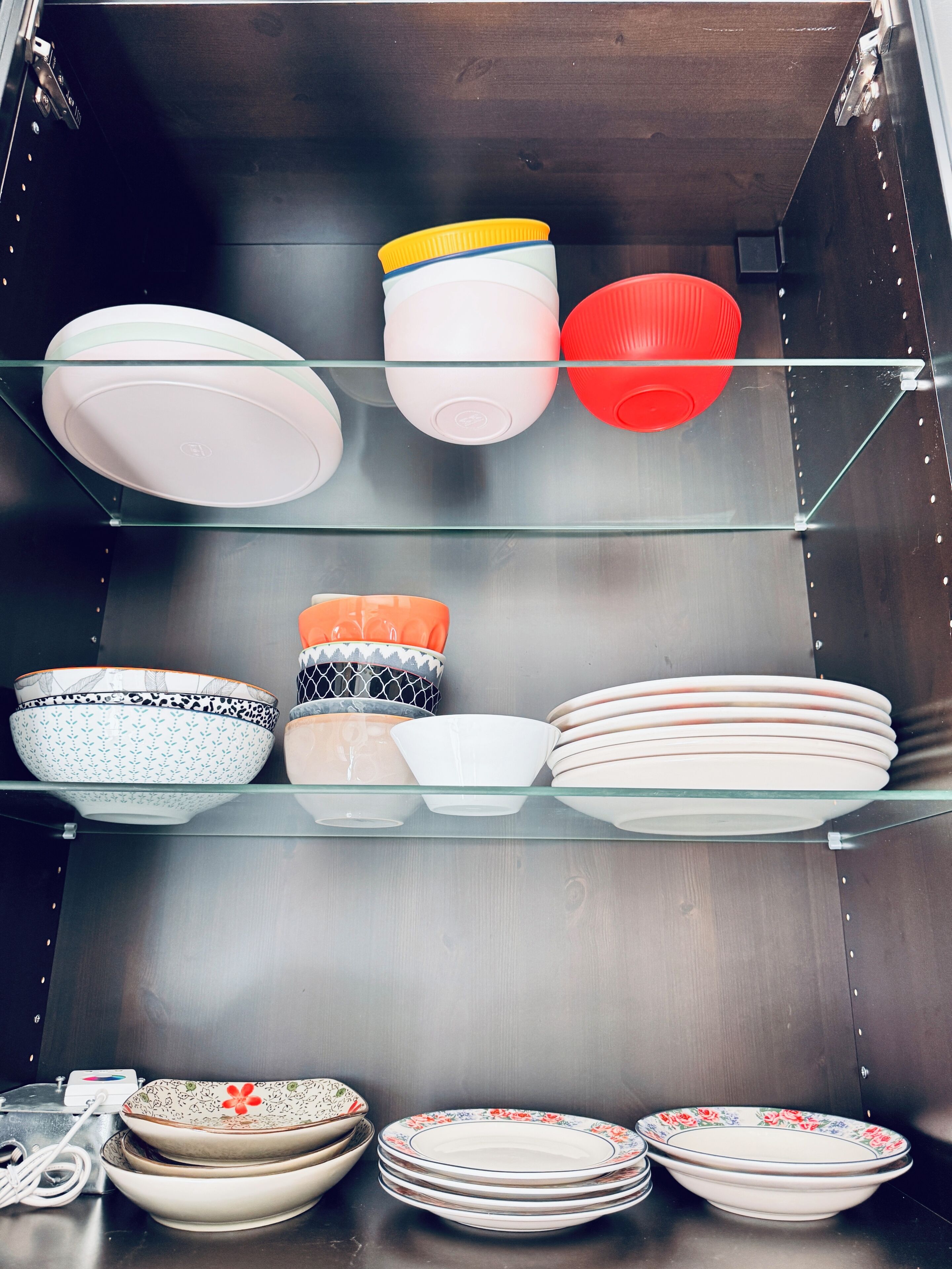 A kitchen with glass shelves holding various bowls and plates.