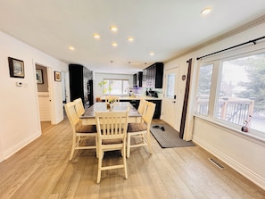 Una cocina moderna con suelo de madera, una mesa de comedor con sillas y un ventanal con vistas al exterior.