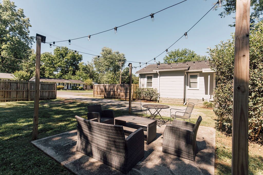 A backyard with outdoor furniture, a wooden fence, and a house in the background.