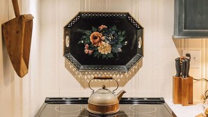 Una cocina con estufa, una campana de madera y un espejo decorativo de forma octogonal.