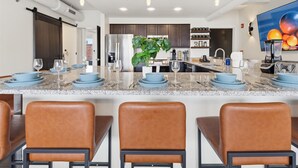 Una cocina moderna con una isla central, electrodomésticos de acero inoxidable y una planta grande.