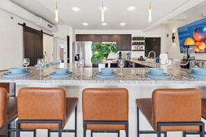 Una cocina moderna con una isla central, electrodomésticos de acero inoxidable y una planta grande.