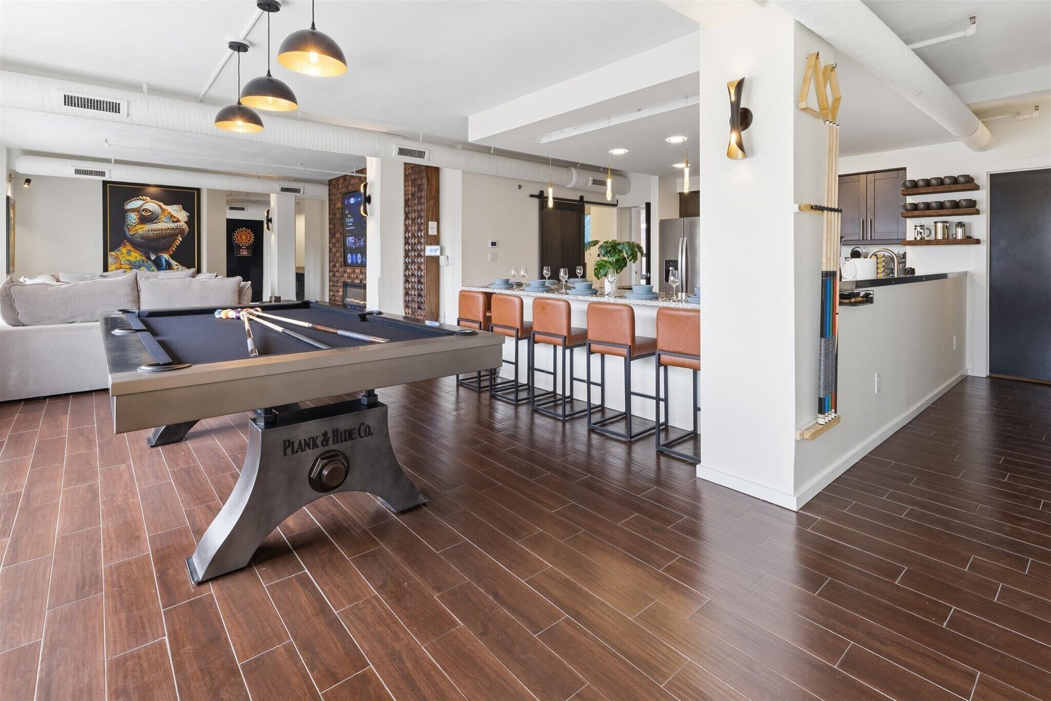 A pool table in a modern living room with a sofa and a kitchen area in the background.
