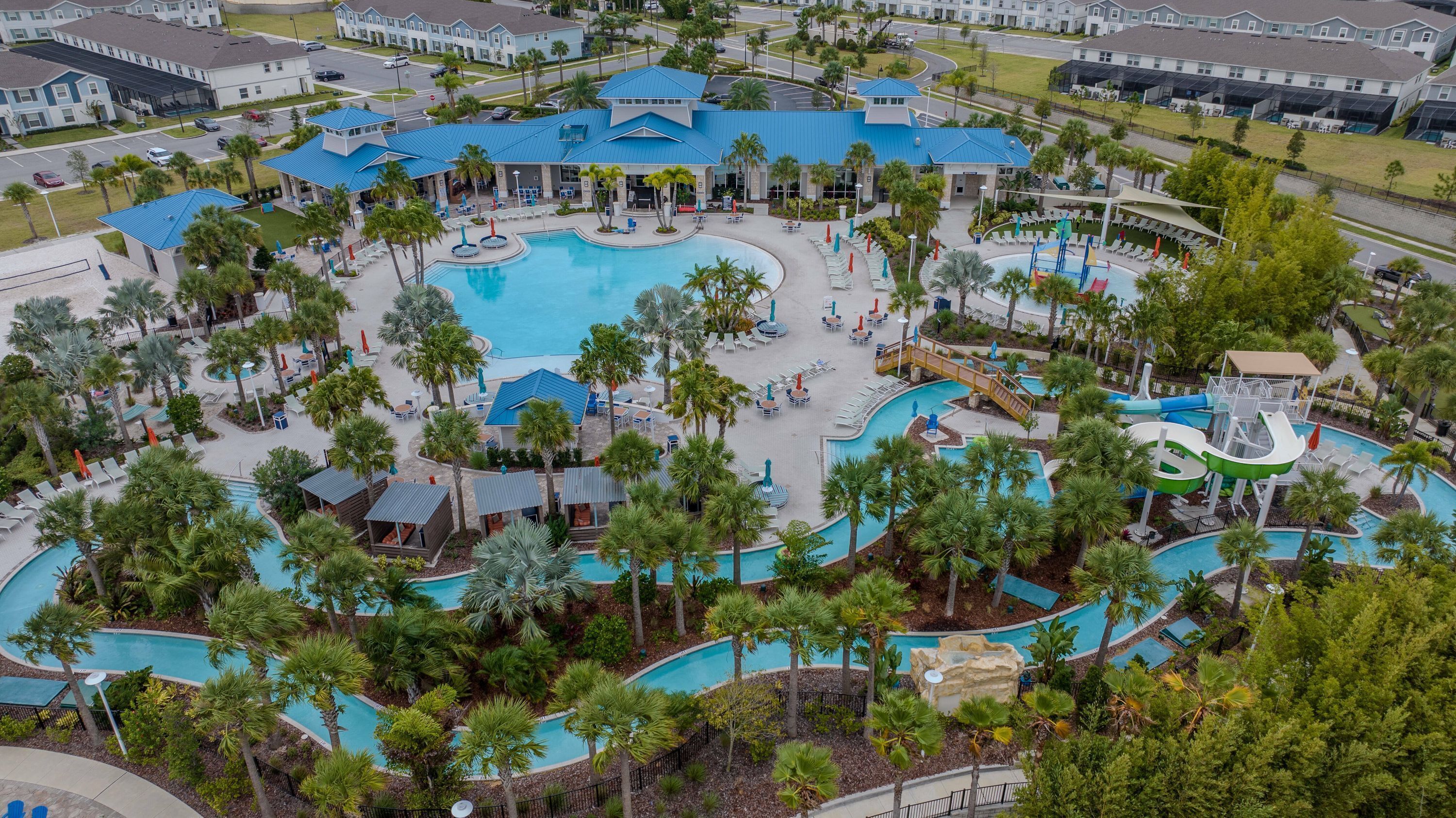 Um resort com várias piscinas, palmeiras e um prédio grande com telhado azul.