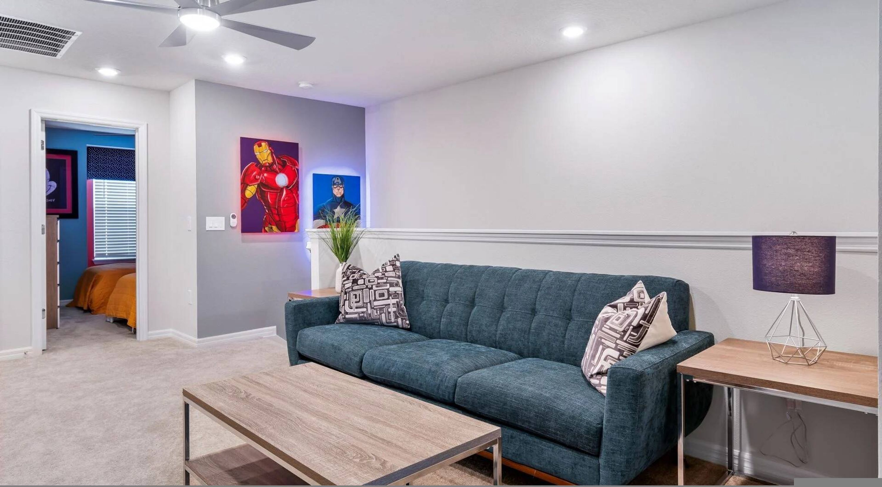 A living room with a sofa, a coffee table, a lamp, and wall art.