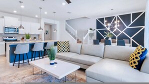 A modern living room with a sofa, a coffee table, and a kitchen area with a bar. - Go 36 - Windsor Island (Davenport)