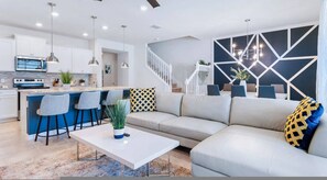 A modern living room with a sofa, a coffee table, and a kitchen area with a bar. - Go 36 - Windsor Island (Davenport)