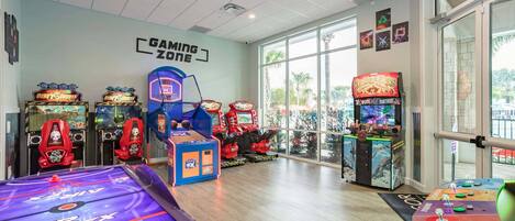 A gaming zone with arcade machines, a pool table, and large windows.