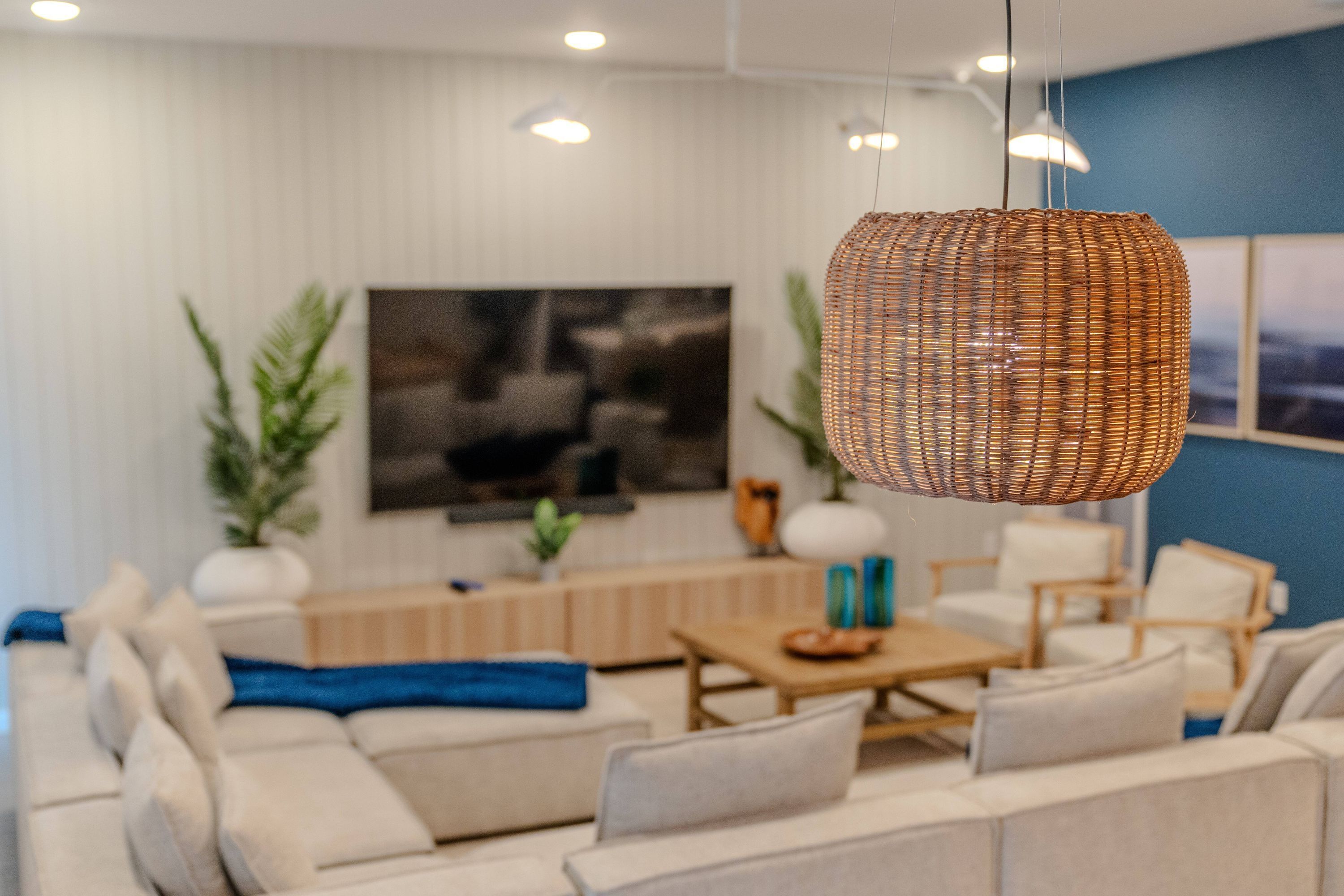 Ein modernes Wohnzimmer mit einer Sofagarnitur, einem Couchtisch und einer hängenden Korbschwinge als Lampe.