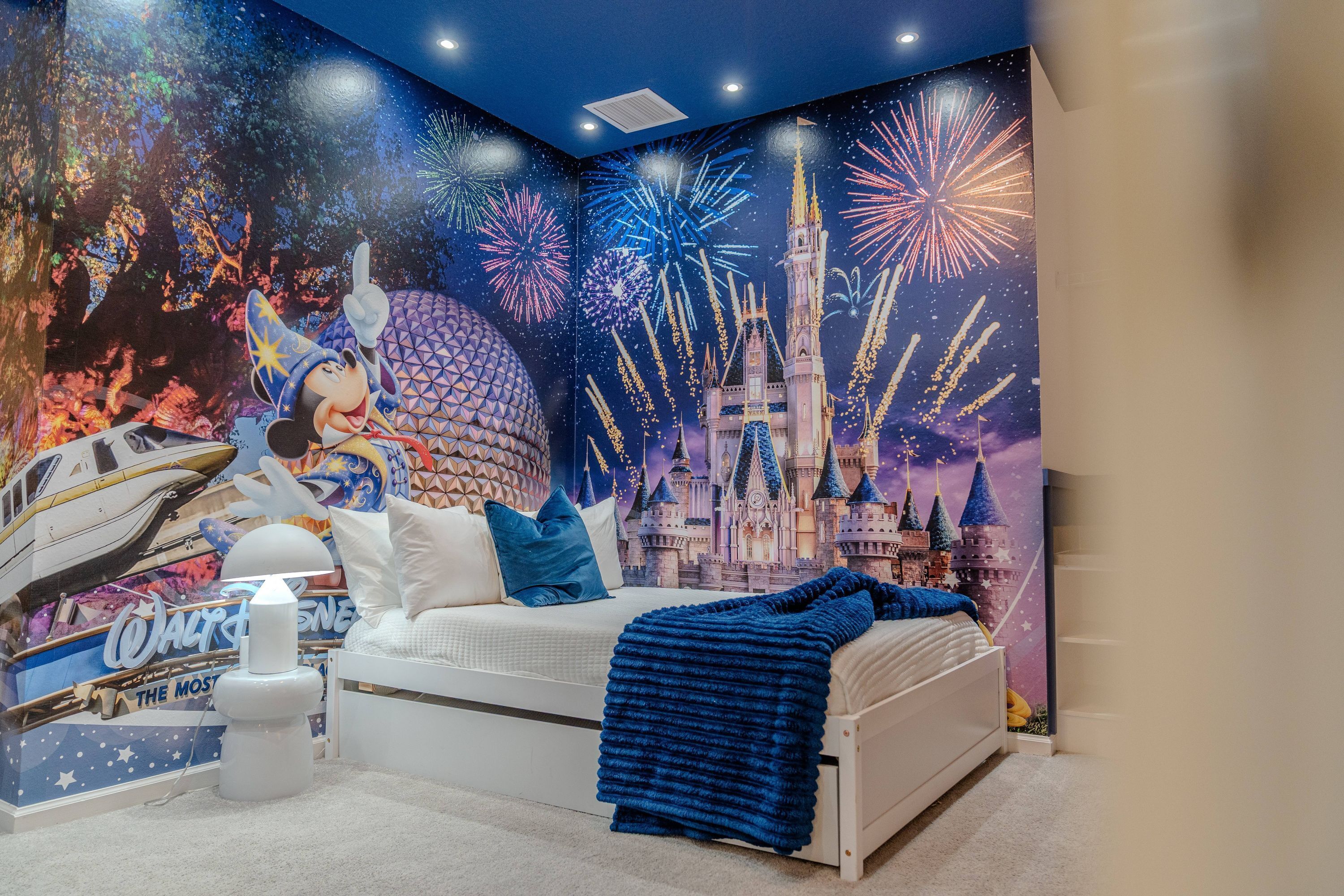 Ein Schlafzimmer mit einem Bett, Kissen, einer Decke, Wandmalerei und einer Mickey Mouse Figur.