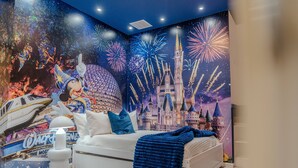A bedroom with a bed, pillows, a blanket, a wall mural, and a Mickey Mouse figure. - Go 39 - Paradiso Grande (Orlando)
