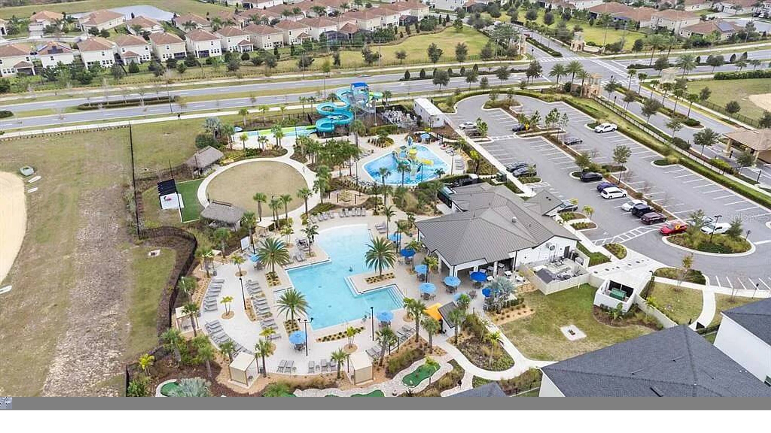 An aerial view of a resort with a swimming pool, water slides, and a parking lot.