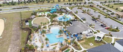 An aerial view of a resort with a swimming pool, water slides, and a parking lot.
