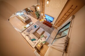 A modern interior with a dining area, sofa set, TV, and a staircase. - Go 40 - Magic Village Views (Kissimmee)