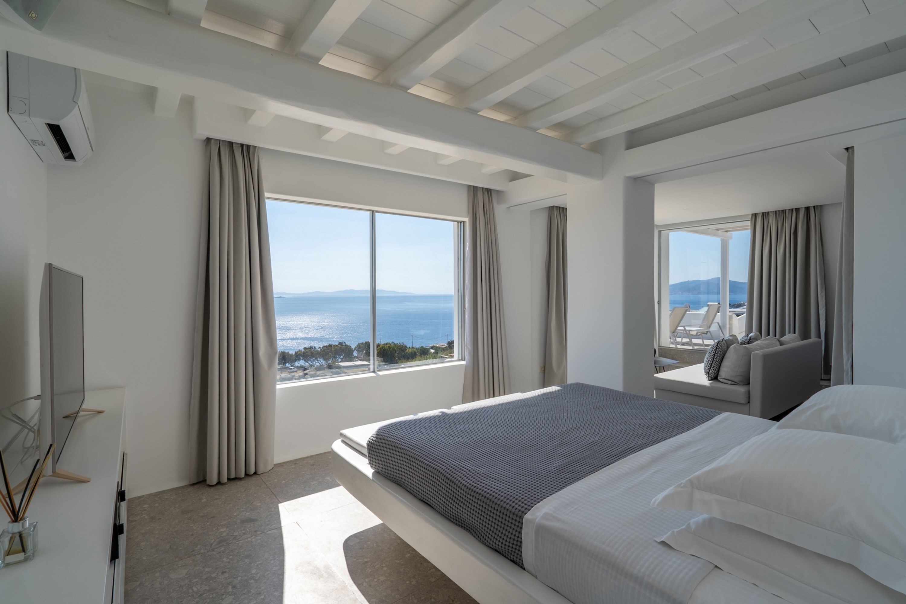 Habitació d'hotel moderna amb un llit gran, televisió i vista al mar.