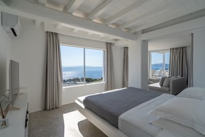 A modern hotel room with a large bed, a TV, and a view of the sea. - Villa Med in Mykonos (Mykonos)