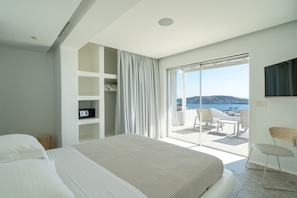 A modern hotel room with a large bed, a TV, a wardrobe, and a balcony with a view of the sea. - Villa Med in Mykonos (Mykonos)