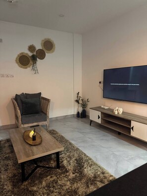 Ein modernes Wohnzimmer mit einer Couch, einem Couchtisch, einem Flachbildfernseher, Wanddekoration und einem Holz-TV-Möbel.