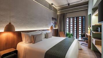 Una habitación de hotel moderna con una cama grande, mesitas de noche, un escritorio y vistas al exterior a través de una ventana.