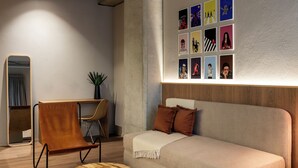 Una habitación moderna con sofá, una silla de madera, una mesa redonda y una pared decorada con cuadros.
