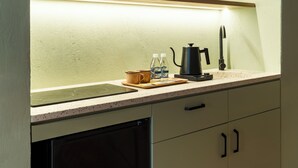 Una cocina con mostrador, tetera, cafetera y lavabo.