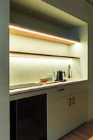 Una cocina con mostrador, tetera, cafetera y lavabo.