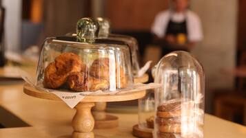 Une vitrine de pâtisserie présentant des viennoiseries sous des cloches de verre, le tout posé sur un présentoir en bois.