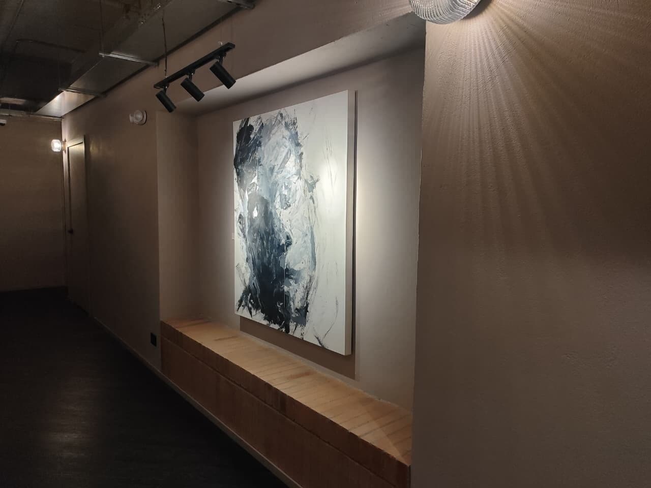 Un couloir avec un banc et un grand tableau abstrait accroché au mur.