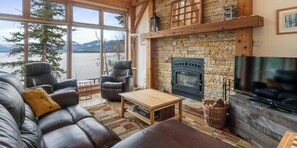 A cozy living room with a stone fireplace, leather sofa, and a television.
