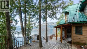 Ein Holzdeck mit Geländer, das auf einen See mit einer hohen Baumumrandung blickt.